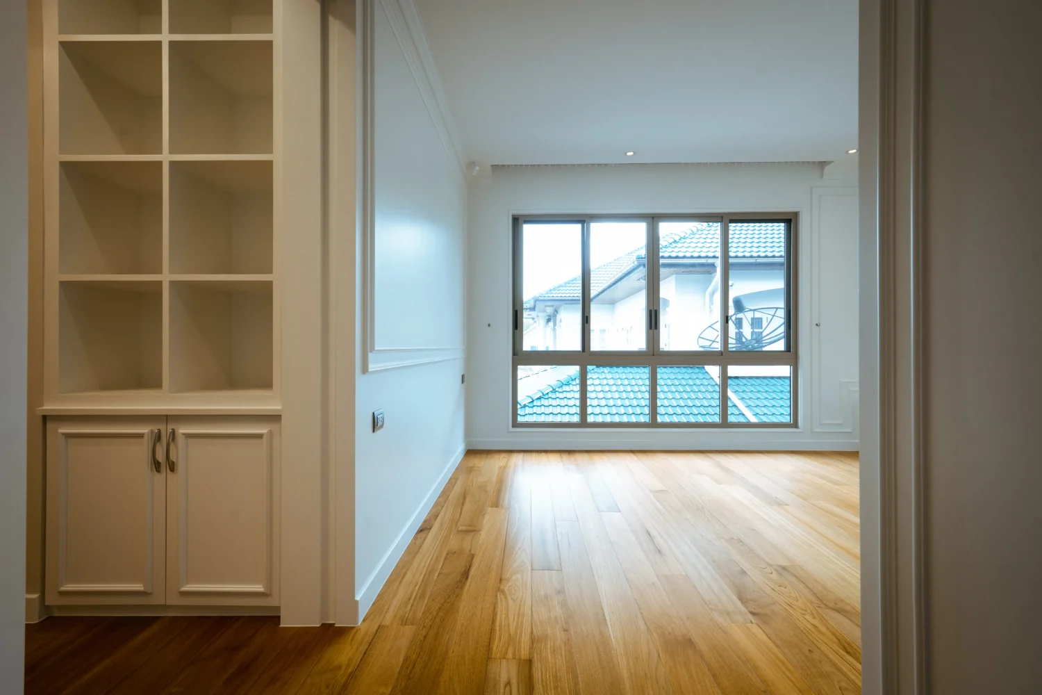 ห้องนอนว่างตกแต่งบิ้วอินตู้สีขาว ปูพื้นไม้จริงโทนสีสว่าง