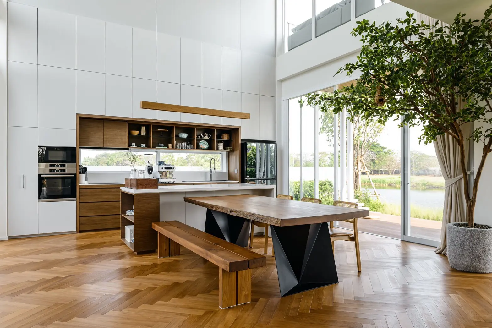 ห้องรับประทานอาหารเพดานสูง ปูพื้นไม้จริงลายก้างปลา (Herringbone) เข้ากับโต๊ะไม้สัก