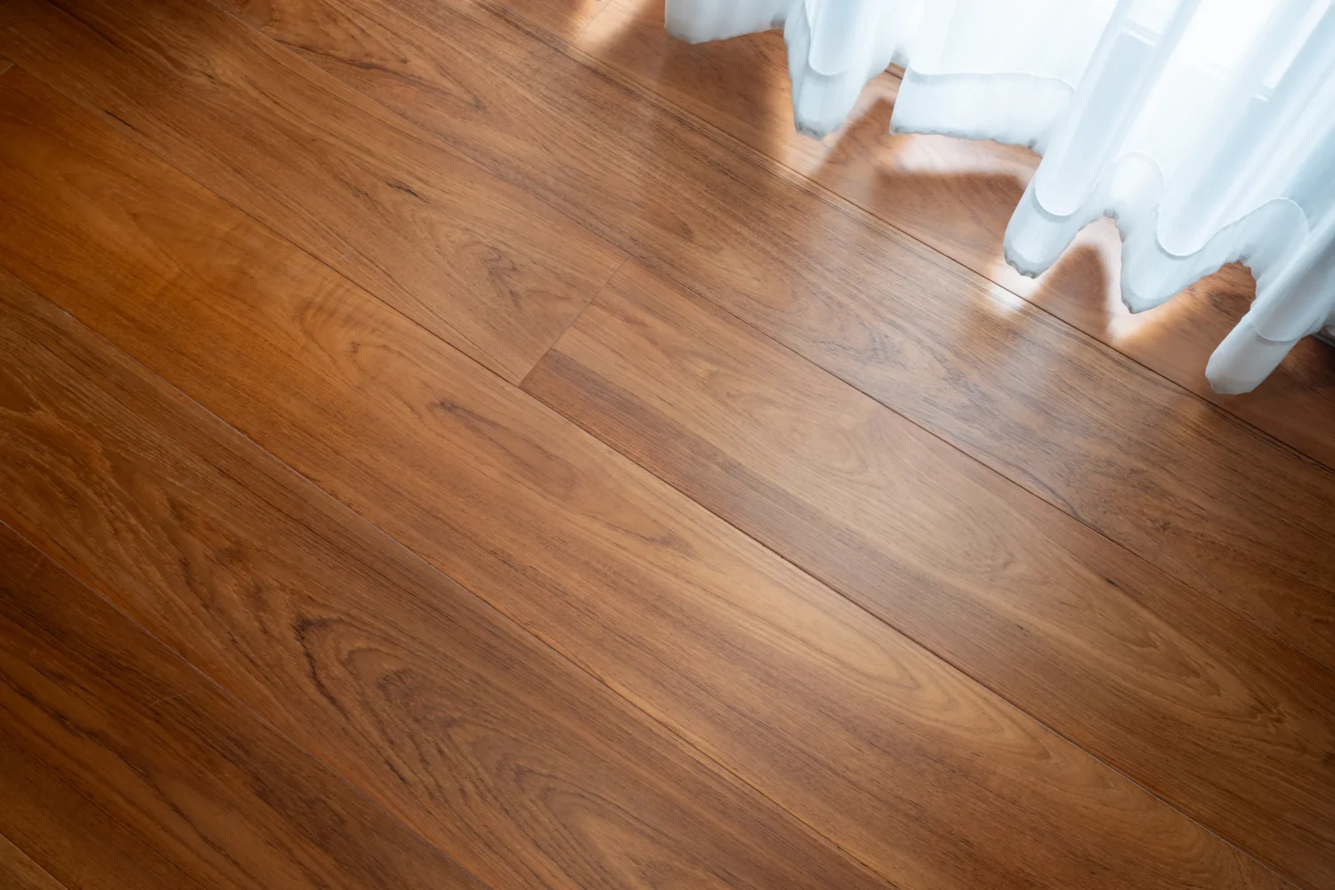 ลายไม้สักพม่า ดีไหม? ภาพระยะใกล้ของพื้นไม้สักสีน้ำตาลทอง ลายไม้สวยงามและเสี้ยนไม้ตรง เห็นรอยต่อไม้ชัดเจน